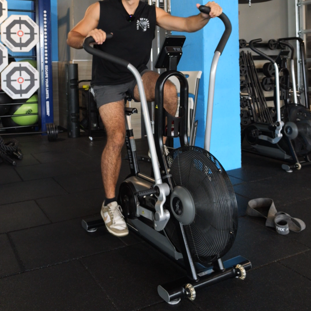 Miami personal trainer performing high-intensity cardio on assault bike for metabolic conditioning